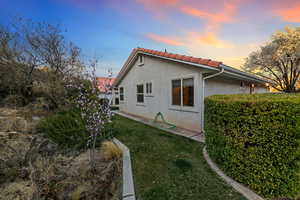View of home's exterior with a yard, a tiled roof, and stucco siding