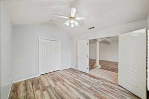 Unfurnished bedroom featuring light wood finished floors, lofted ceiling, a closet, and ceiling fan