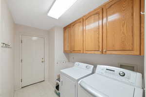 Washroom with cabinet space, washing machine and dryer, and light floors