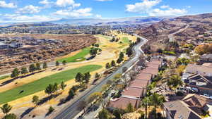 Aerial view of property's location with nearby suburban area, a mountainous background, and a golf course