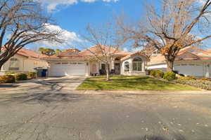 Mediterranean / spanish-style house featuring a tiled roof, driveway, stucco siding, a front lawn, and a garage