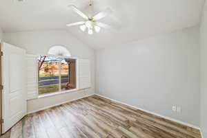 Unfurnished room featuring wood finished floors, vaulted ceiling, and a ceiling fan