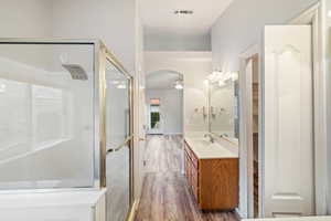 Full bath featuring vanity, a shower stall, ceiling fan, and dark wood-style flooring