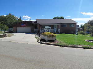 Ranch-style house with driveway, a front lawn, a porch, brick siding, and a garage