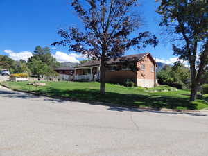 View of front of house with a front yard, a mountain view, and covered porch