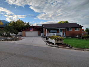 Single story home featuring brick siding, driveway, a porch, and a garage