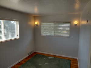 Bedroom 3 with a textured ceiling and wood finished floors