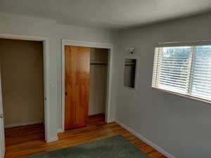 Bedroom 3 featuring a textured ceiling, light wood finished floors, and a closet