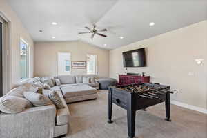 Recreation room with light colored carpet, plenty of natural light, lofted ceiling, a ceiling fan, and recessed lighting