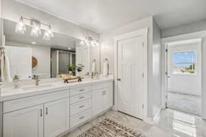 Bathroom with double vanity, a shower stall, and light marble finish floors