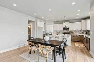 Dining room with light wood-style flooring and recessed lighting
