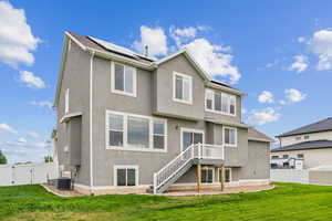 Back of house with a fenced backyard, stucco siding, and roof mounted solar panels