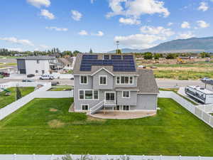 Back of house featuring solar panels, roof with shingles, a fenced backyard, and stucco siding