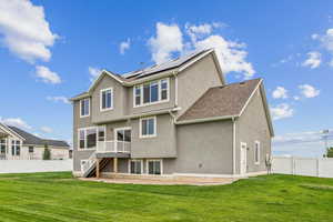 Rear view of property featuring a fenced backyard, stucco siding, solar panels, a patio area, and a wooden deck