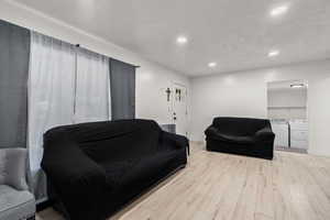Living room featuring recessed lighting, wood finished floors, washing machine and clothes dryer, and a textured ceiling