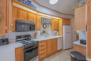 Kitchen with white appliances, light countertops, and ornamental molding