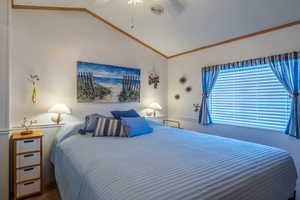 Bedroom with crown molding, ceiling fan, vaulted ceiling, and carpet flooring