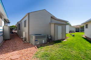 View of property exterior with a cooling unit and a lawn