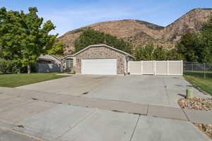 View of front of home with a mountain view, stone siding, a gate, driveway, and an attached garage