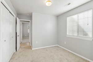 Unfurnished bedroom featuring light carpet and a closet