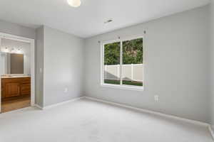 Unfurnished bedroom featuring light carpet and connected bathroom