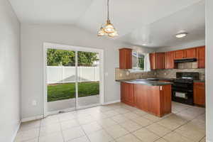 Kitchen featuring backsplash, a peninsula, black range, light tile patterned flooring, and hanging light fixtures