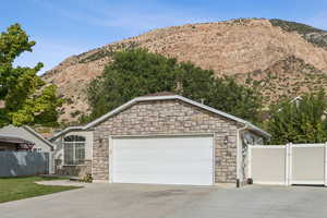 View of front of house featuring stone siding, a gate, driveway, and a mountain view