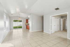 Unfurnished living room with light tile patterned floors and vaulted ceiling