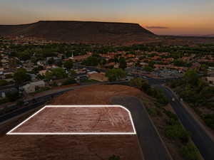 Aerial view of residential area with property boundaries highlighted and a mountainous background