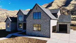 View of front facade with stone siding, concrete driveway, and a mountain view
