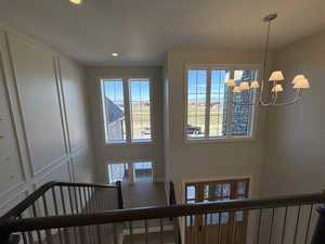 Stairway with suspended lighting, a decorative wall, and a high ceiling