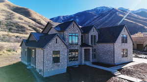 View of front of home featuring a mountain view, stone siding, and a shingled roof