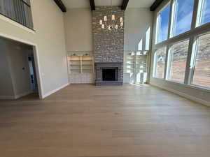 Unfurnished living room featuring a fireplace, light wood-type flooring, built in features, and suspended lighting