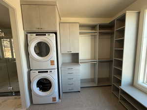 Primary Closet with stacked washer and clothes dryer and a textured ceiling