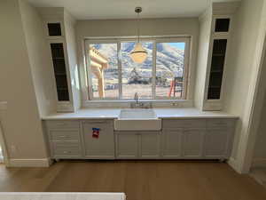 Kitchen featuring glass fronted cabinets, hanging light fixtures, and light wood-style floors