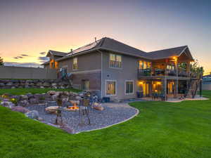 Back of house at dusk with a patio, stairway, a fire pit, and stucco siding