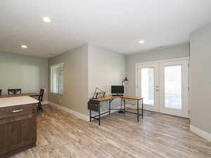 Office space featuring light wood-style floors, french doors, recessed lighting, and a textured ceiling