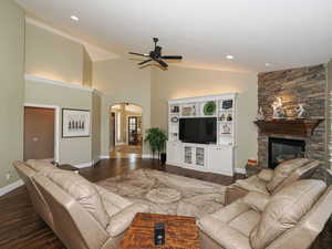 Living room with arched walkways, dark wood-type flooring, high vaulted ceiling, a ceiling fan, and recessed lighting