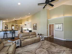 Living area featuring high vaulted ceiling, dark wood finished floors, recessed lighting, and a ceiling fan