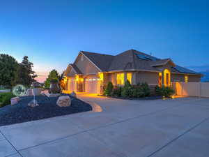 View of front of home featuring stucco siding, driveway, roof mounted solar panels, an attached garage, and a shingled roof