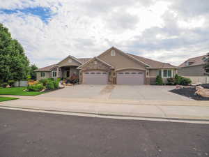 View of front facade with driveway, stucco siding, a garage, and stone siding