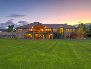 Rear view of house featuring a lawn, stairway, a patio, a balcony, and stucco siding