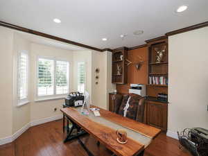 Home office with dark wood-style floors, crown molding, and recessed lighting