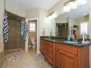 Bathroom featuring light tile patterned floors, double vanity, and a stall shower