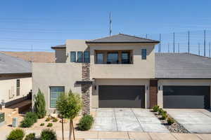 View of front of house featuring driveway, a garage, stucco siding, a tiled roof, and a balcony