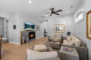 Living area featuring light wood-style flooring, a tile fireplace, ceiling fan, and recessed lighting