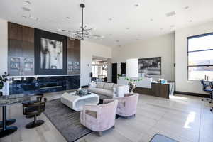 Living room with a high ceiling, a chandelier, light tile patterned floors, a desk, and recessed lighting