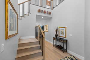 Staircase featuring wood finished floors and a high ceiling