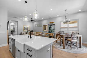 Kitchen featuring light wood-type flooring, white cabinets, pendant lighting, a kitchen island with sink, and a ceiling fan