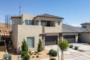 Contemporary home with concrete driveway, stucco siding, a garage, and a tile roof